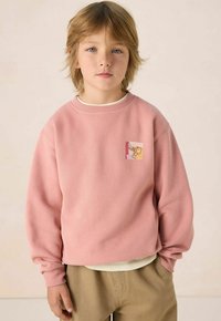 Roze sweatshirt van zacht materiaal, met een ronde halslijn en geribbelde mouwen. Inclusief een klein grafisch label op de borst.