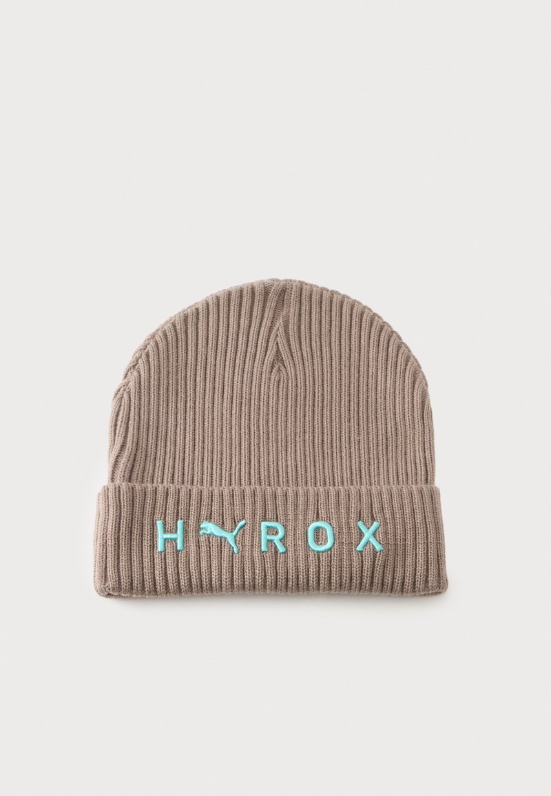 Bonnet en maille côtelée beige avec revers plié, brodé du logo PUMA bleu et des lettres H, R, O, X à l'avant.