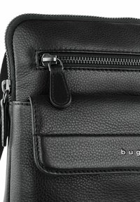 Borsa in pelle nera con superficie testurizzata, dotata di una tasca con zip e accessori in metallo argentato. Include una tasca frontale con patta e dettagli di cucitura.