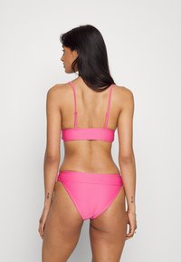 Conjunto de bikini rosa com um acabamento texturizado; possui alças finas ajustáveis e uma cintura sem costura na parte inferior.