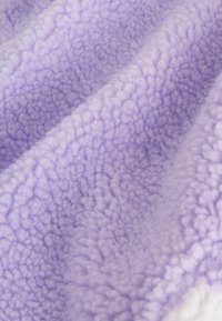 Țesătură de fleece violet cu o suprafață moale și texturată, având un pui gros și pufoasă, cu variații subtile în intensitatea culorii.