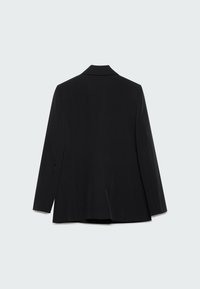 Veste noire cintrée à manches longues vue de dos sur un fond clair uni.