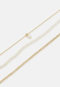 Cadena en tono dorado, hilo de perlas blancas y eslabones dorados alternos. Texturas suaves con una mezcla de cuentas pequeñas y eslabones más grandes.
