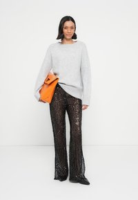 Hall triiksärk laiade varrukatega, ühendatud kõrge vöökohaga mustade litritega lehvivate pükstega. Modell hoiab oranži käekotti. Mustad kontsakingad.