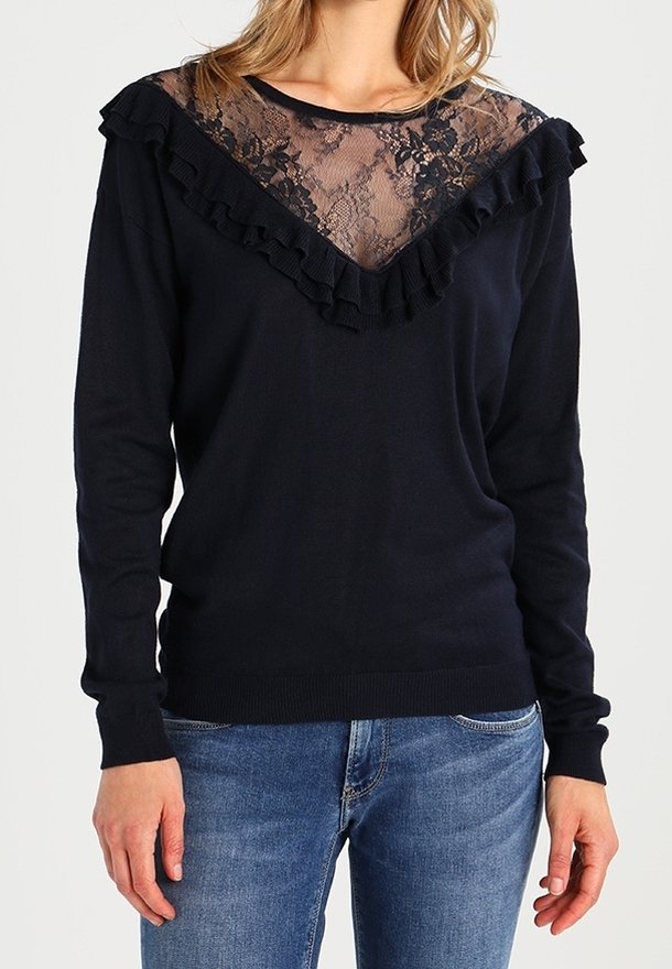 Marineblauer Pullover mit Spitzenbesatz und Rüsche am Kragen. Lange Ärmel und gerippten Bündchen. Kombiniert mit blauen Jeans im lässigen Schnitt.