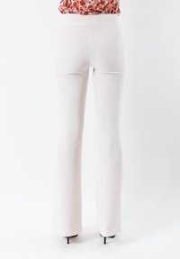 Pantaloni svasati bianchi con una texture liscia e una vita alta. Progettati con uno stile minimalista e una silhouette aderente fino all'orlo.