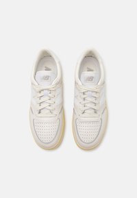 Białe skórzane sneakersy z perforowanym przodem, jasnoszarymi akcentami i gumową podeszwą o subtelnym żółtym odcieniu. Sznurowadła są w komplecie.