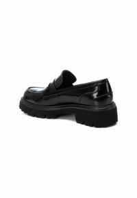 Mocassino in pelle nera con finitura lucida, dotato di una suola in gomma nera spessa e un dettaglio cucito rialzato sulla punta.