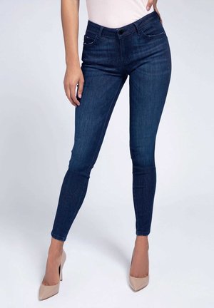 Kapeempparit tummansinisestä denimmistä, korkea vyötärö, jossa etutaskut ja huomaamaton ompelu. Yhdistetty nude-sävyisiin korkeisiin korkoihin.