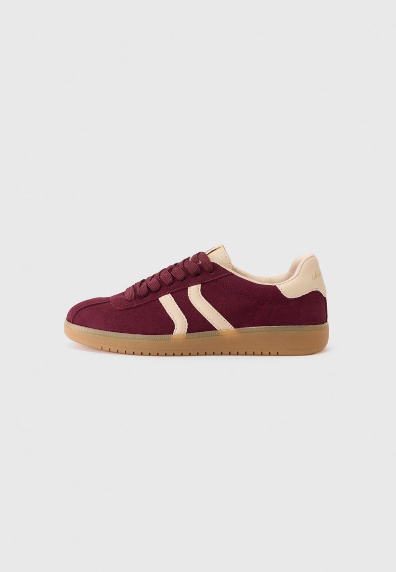 Burgunderfargede semskede sneakers med kremfargede detaljer, rund tå, flat gummisåle og snøring med to diagonale striper på siden.