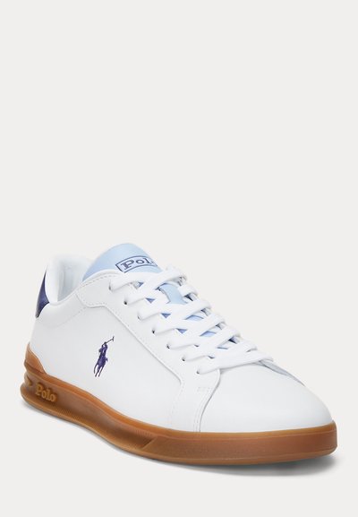 Vita lädersneaker med ljusblå accenter och brun gummisula. Funktioner inkluderar rund tå, snörning framtill och broderad logotyp.