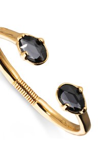 Brazalete de tono dorado con dos piedras negras en forma de pera, acabado liso y detalle de torsión en la banda.