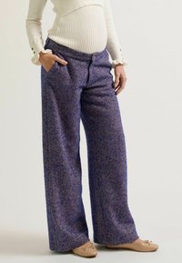 Weite Hosen aus lila Fischgrätstoff mit strukturiertem Finish, ausgestattet mit Seitentaschen und einem lässigen Schnitt. Kombiniert mit leichten Ballerinas.