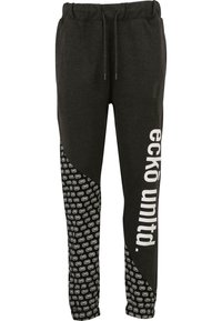 Sorte sweatpants med snøre i taljen, et hvidt logo og tekst på forsiden samt et mønstret sidepanel med gentagne designs.