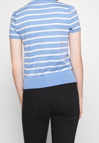 Blå och vit randig kortärmad topp med ribbad halsringning och nederkant, matchad med svarta jeans med bakfickor.