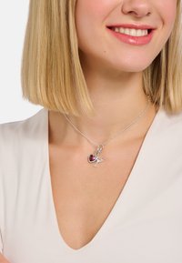 Silberne Halskette mit zwei Anhängern: ein rotes Herz und ein Cocktailglas, die an einer zarten Kette mit strukturierter Oberfläche hängen.