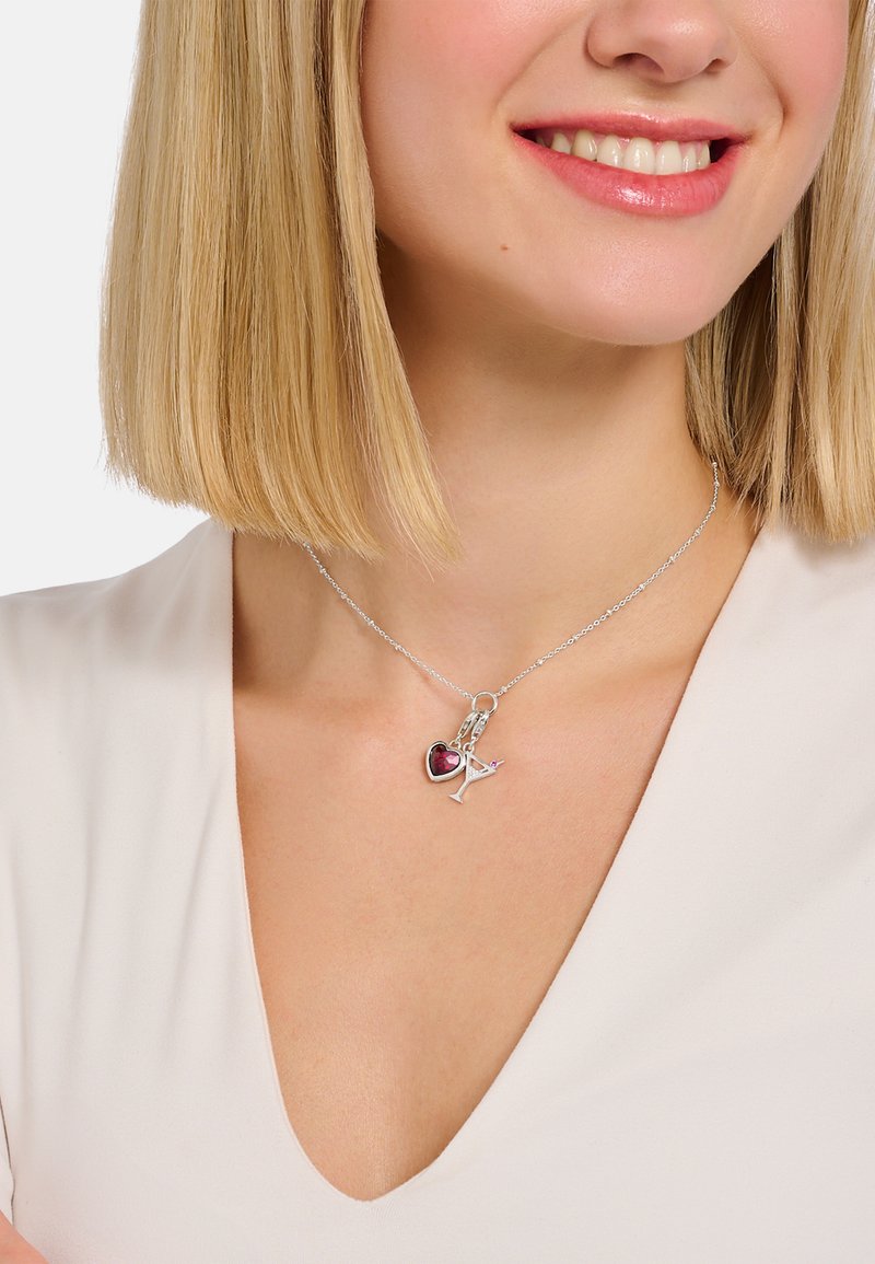 Silberne Halskette mit zwei Anhängern: ein rotes Herz und ein Cocktailglas, die an einer zarten Kette mit strukturierter Oberfläche hängen.