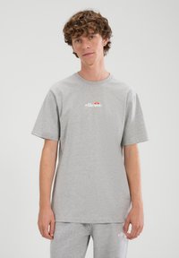 Grijs katoenen T-shirt met korte mouwen, een ronde hals en een wit logo met rode en gele accenten. Eenvoudig ontwerp, ontspannen pasvorm.