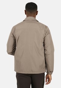 Lekka beżowa kurtka o gładkiej fakturze, z kołnierzem, elastycznymi mankietami i prostym wzornictwem. Widok z tyłu pokazuje szczegóły szwów.