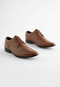 Brown leather shoes with a sleek design, pointed toe, and lace-up closure; textured upper and a low black heel.