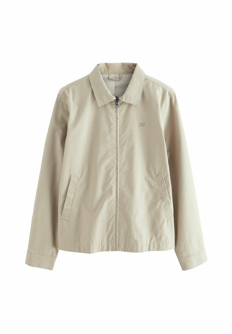 Veste légère beige avec un col, fermeture éclair devant et deux poches latérales. Texture lisse avec un détail de logo discret sur la poitrine.