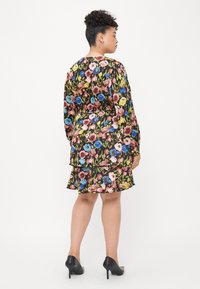 Floral dress featuring vibrant multicolored flowers on a black background, long sleeves, and a tiered design with a flared hem.