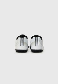 White athletic shoes with black accents, mesh upper, and textured rubber outsole. Includes a vertical striped detail on the heel.