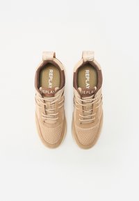 Baskets en mesh et suède beige présentant un bout arrondi, un laçage classique, et un accent de talon marron avec la marque "REPLAY" sur la languette et la semelle intérieure.