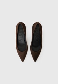 Brune semskede spisse pumps med en glatt svart indre fôr og preget "FURLA"-logo på sålen. Ingen synlig maskinvare eller detaljer.