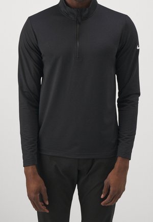Mann trägt einen schwarzen Langarm-Halbzip-Pullover mit weißem Nike-Logo am linken Ärmel.