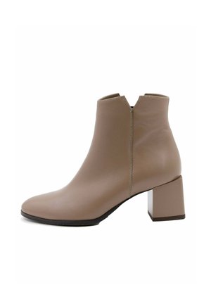 Bottines beiges en cuir lisse, avec un petit talon carré, un bout pointu et une fermeture éclair à l'arrière.