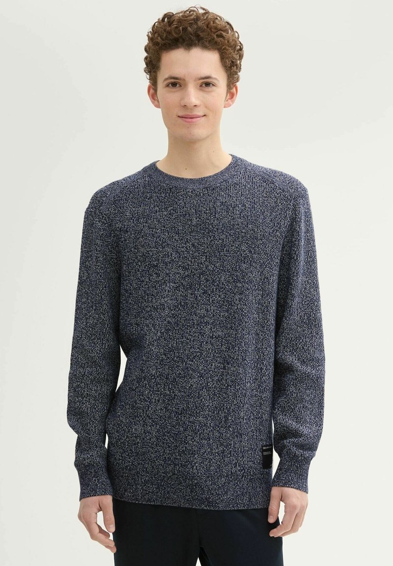 Miodowy granatowy sweter dzianinowy z długimi rękawami, okrągłym dekoltem i fakturowanym materiałem. Posiada metkę na dolnej lewej stronie.