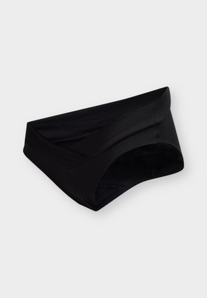 Braguitas negras de mujer con una cinturilla ancha doblada, sobre un fondo liso y claro.