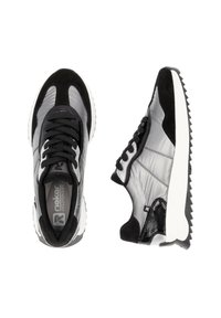 Chaussures de sport noires et grises avec un mélange de matériaux synthétiques lisses et de daim, dotées de semelles blanches et de crampons en caoutchouc texturés.