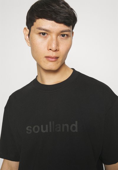 Černé bavlněné tričko s tónovým logem "soulland". Klasický kulatý výstřih a krátké rukávy s volným střihem. Hladká textura.