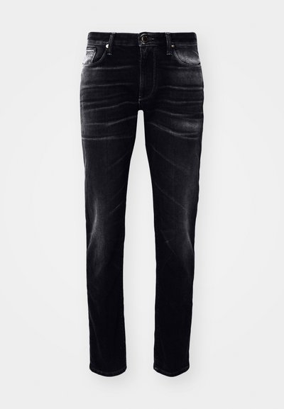 Jeans de mezclilla negra con un corte ajustado, que presentan un diseño de cinco bolsillos, costuras visibles y un ligero desgaste a lo largo de las piernas.