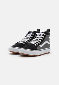 Sneaker alte in suede nero e grigio, con lacci bianchi e suola in gomma con un motivo testurizzato. Presenta un dettaglio del logo sulla linguetta.