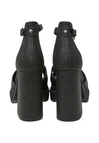 Sandalias de tacón alto negras brillantes con un tacón grueso y tira al tobillo. Acabado texturizado y acentos metálicos en tono plateado en la tira.