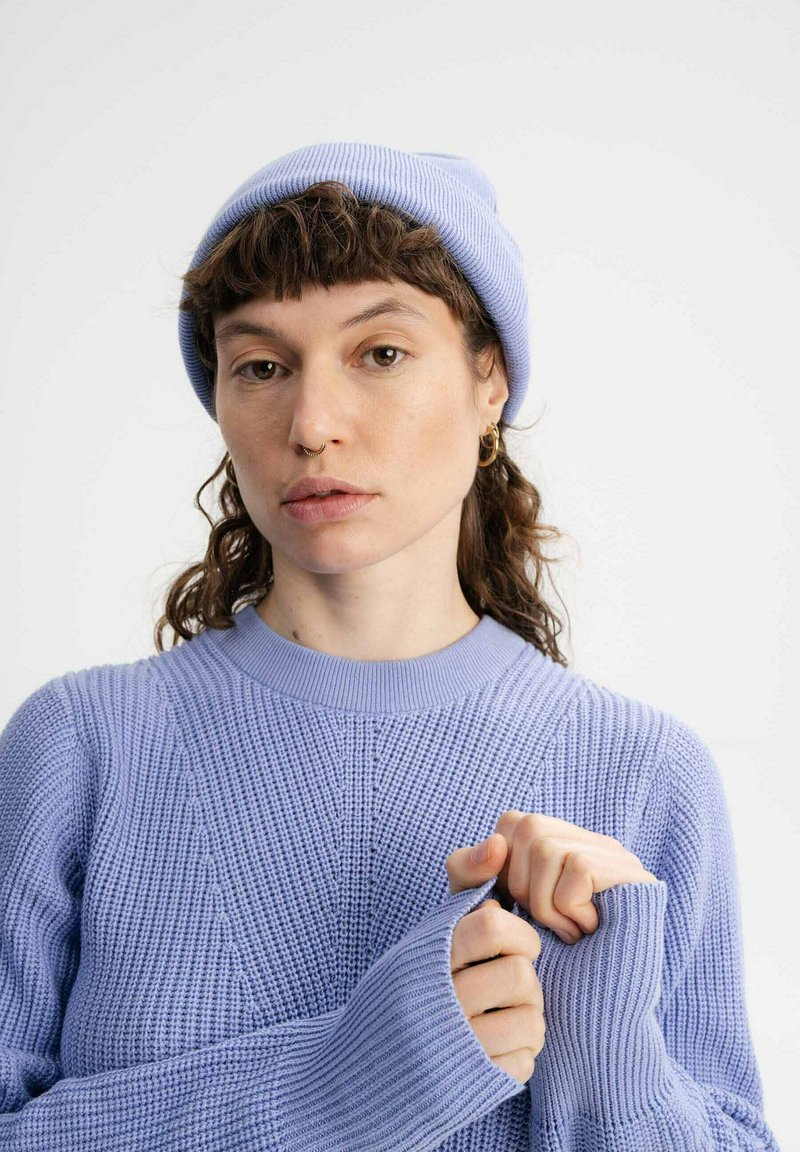 Lichtpaarse geribbelde gebreide trui met een ronde hals, voorzien van gestructureerde patronen en verlengde mouwen, gecombineerd met een bijpassende muts.