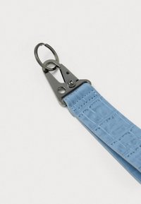 Lyseblå tekstureret læderrem med præget mønster, der har en metallisk clips og ring hardware til fastgørelse.