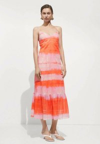 Maxi haljina u ružičasto-narančastom tie-dye uzorku. Slip stil s tankim naramenicama i lepršavim rubom. Lagana tkanina i jednostavan dizajn.