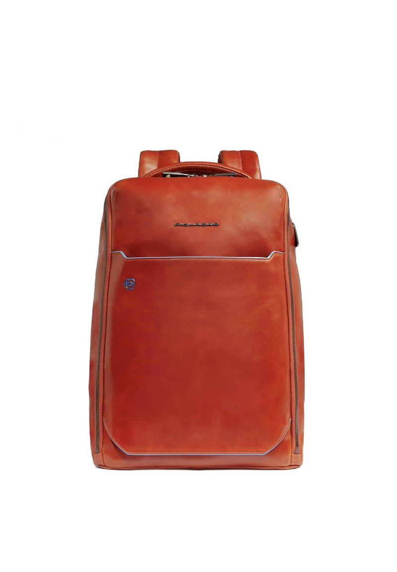 Mochila de cuero marrón con correas ajustables dobles, un asa superior, un bolsillo frontal con cremallera y sutil costura de acento azul. Textura suave.