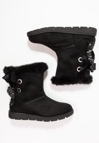 Černé nubukové kotníkové boty s umělým kožíškem a měkkými stužkovými detaily. Obsahují kovové očka a texturovanou gumovou podrážku pro lepší přilnavost.