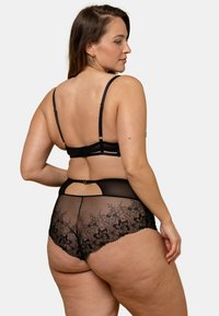 Ensemble de lingerie en dentelle noire avec un motif floral détaillé, dos transparent, et bretelles ajustables avec un fermoir à crochets.