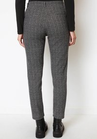 Grå byxor med fiskbensmönster i vävt tyg, slim fit, med midjeresår och bakfickor, kombinerade med svarta ankelboots.