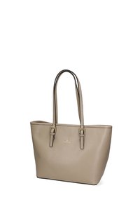 Sac tote en cuir beige, avec une forme structurée, deux longues poignées et un détail logo doré à l'avant. Texture lisse sans motifs visibles.
