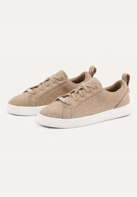 Beige filt sneakers har en rund tå, snörning framtill och en vit gummisula. De har en mjuk textur och en dragflik på baksidan.