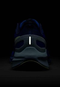 Le scarpe da ginnastica navy presentano una tomaia in rete testurizzata, un contrafforte grigio imbottito e un accento riflettente bianco sul retro.