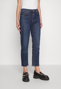 Mörkblå denimjeans med rak passform, femficka-design och subtila sömnadsdetaljer. Bärs med svarta klumpiga loafers.