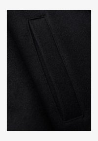 Tela de fieltro negro con una superficie texturizada y una abertura rectangular cosida en el material, presentando bordes y costuras limpias.
